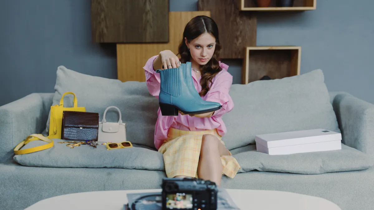 Woman holding up a shoe with shopping items and filming setup