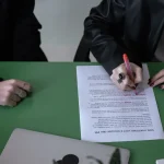 person signing a document at a table