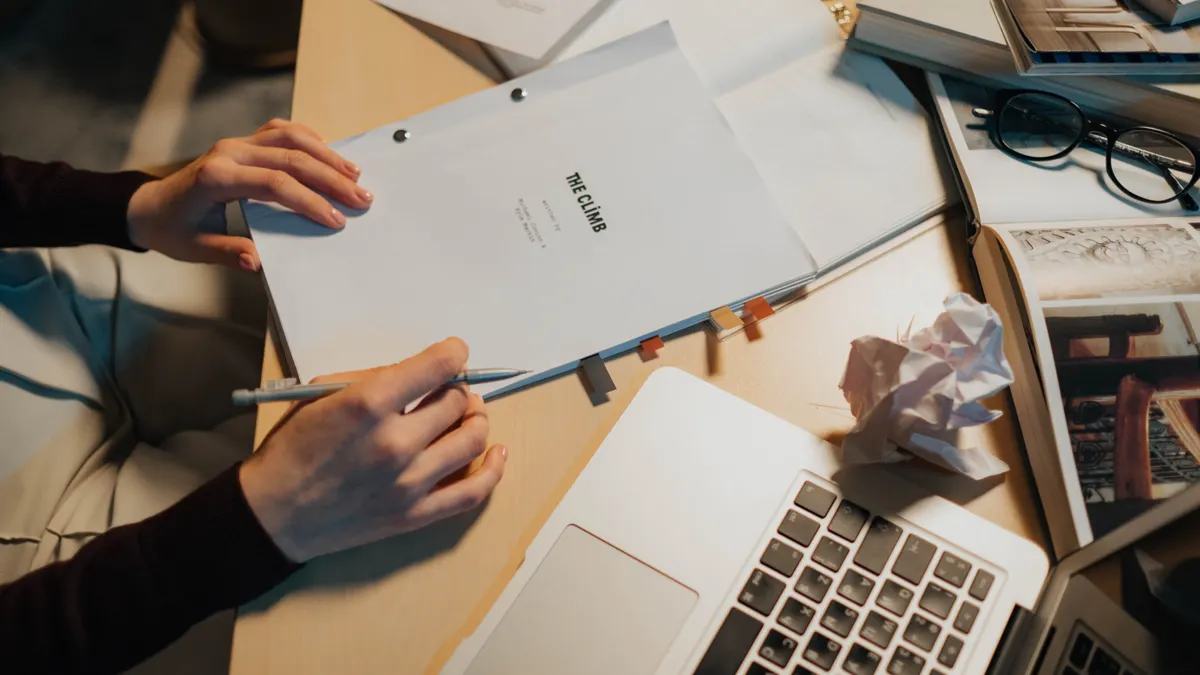 hands reviewing papers beside a laptop