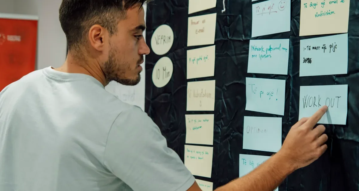 person organizing sticky notes on a planning wall