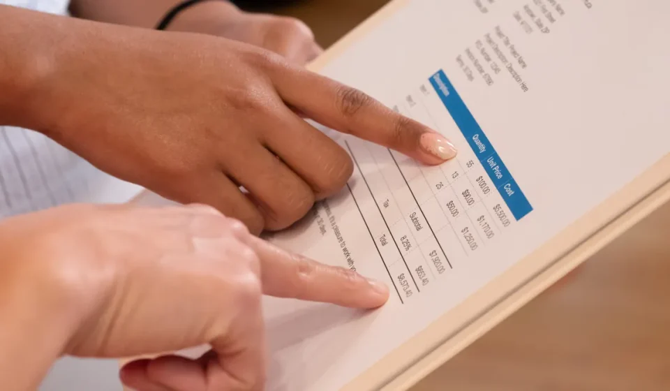 Hands pointing at a printed pricing table