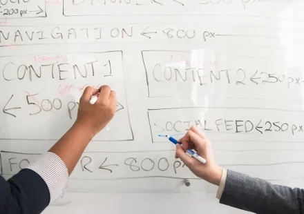 hands sketching a website wireframe on a whiteboard
